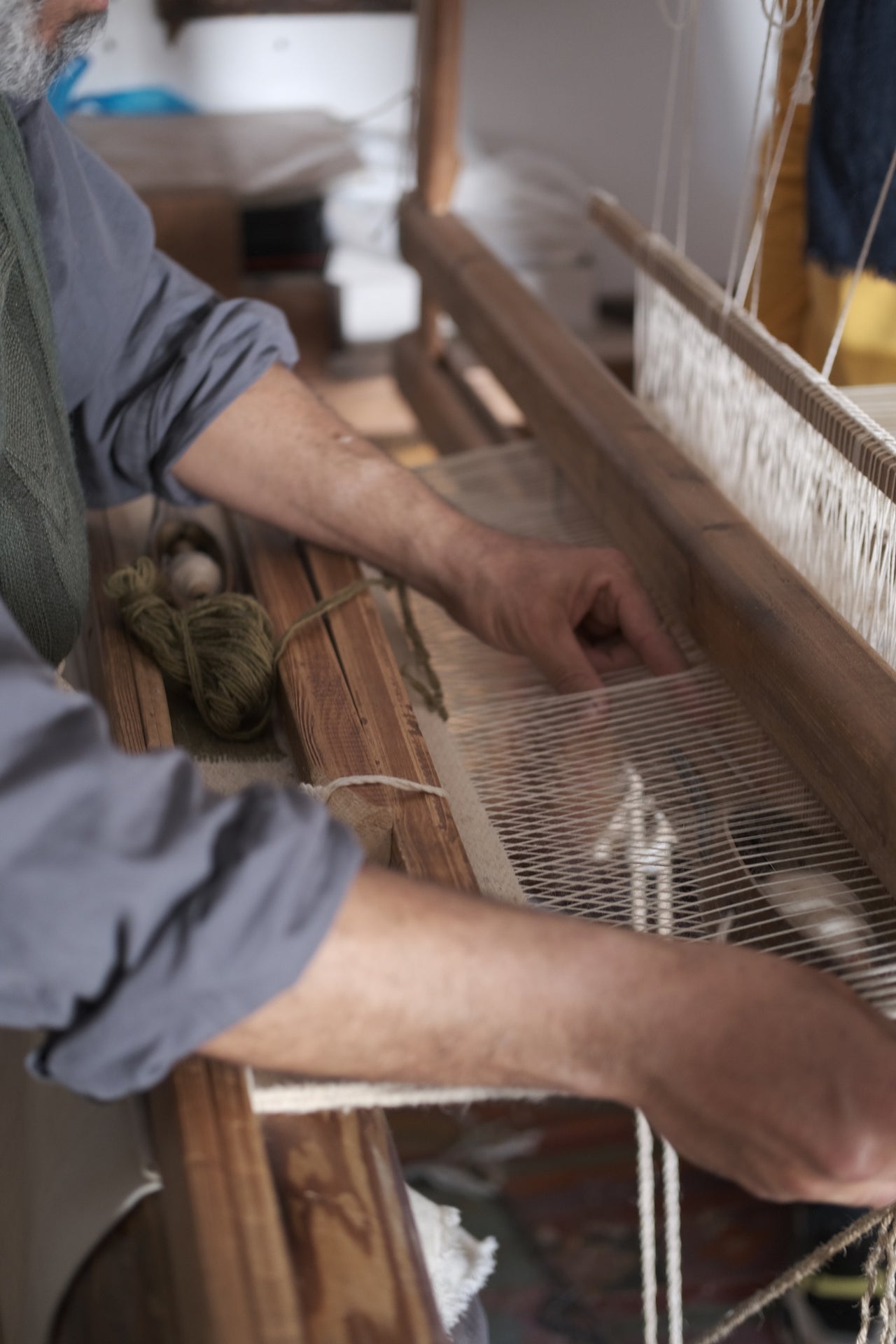 An artisan weaving wool on a wooden loom